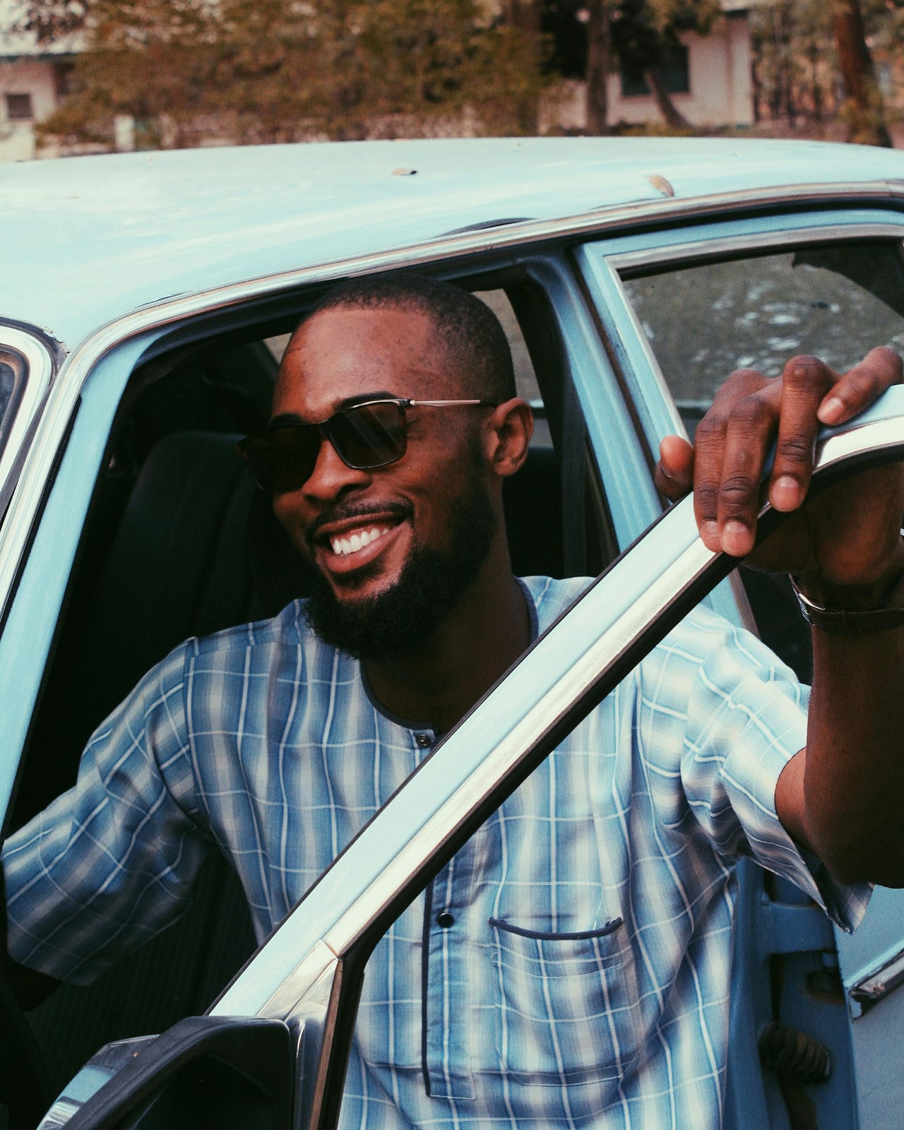 A QuickLyft Founding Driver smiling beside his car after a fairly paid commute